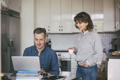 Smiling man and woman workin in kitchen at home