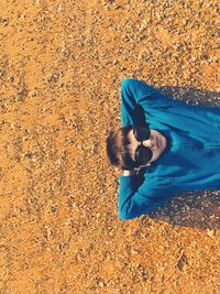 High angle view of boy wearing sunglasses while lying on field during sunny day