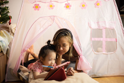Face focusing on asian mom and adorable daughter are lying on the floor in pink tent at home 