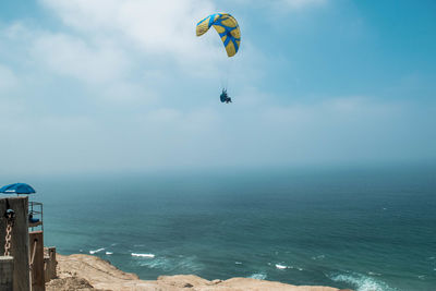 Person paragliding against sea and sky