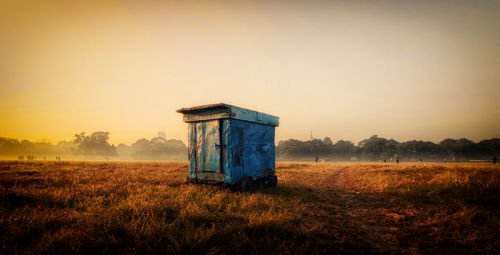 Abandoned barn on field against sky during sunset