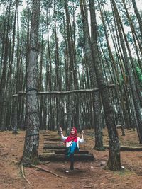 Low angle view of woman enjoying swing in forest