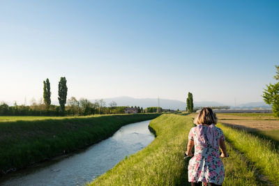 Rear view of woman on grassy field against clear sky