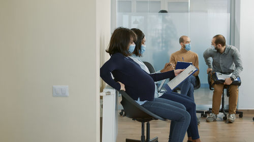 Side view of woman sitting on window