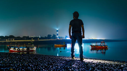 Rear view of man standing in sea against blue sky