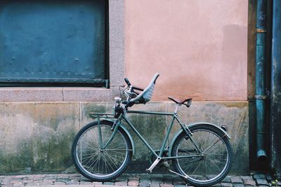 Bicycle leaning against wall on footpath