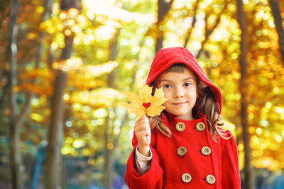 Portrait of girl holding leaf during autumn