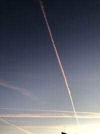 Low angle view of vapor trails against sky during sunset