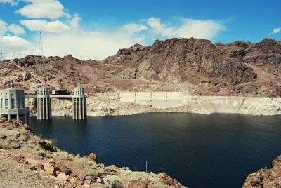 Scenic view of dam and mountains against sky