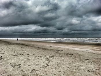 Scenic view of beach against cloudy sky