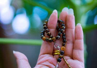 Close-up of woman hand holding jewelry at park