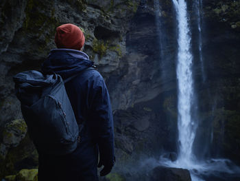 Rear view of man standing against waterfall