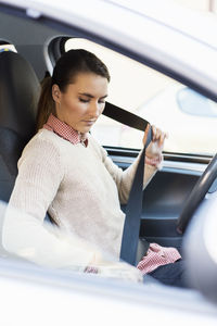 Businesswoman fixing seat belt in car