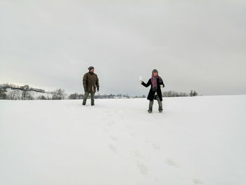 People on snow covered landscape against sky