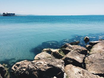 Rocks at beach against clear sky