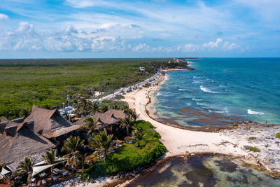 Aerial tulum coastline by the beach with a magical caribbean sea and small huts by the coast.