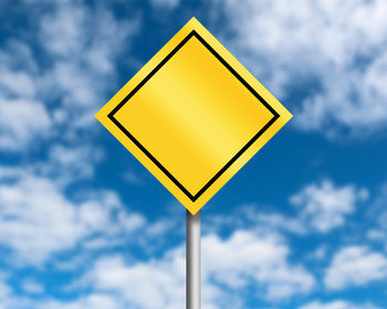 Close-up of yellow road sign against blue sky