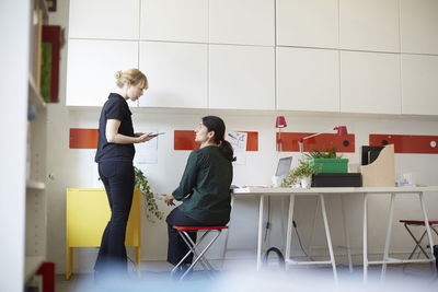 Mid adult businesswoman talking with female colleague in office