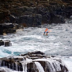 Man surfing on rock by river