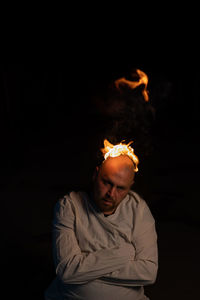 Man holding burning candle against black background