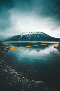 Scenic view of lake by snowcapped mountains against sky