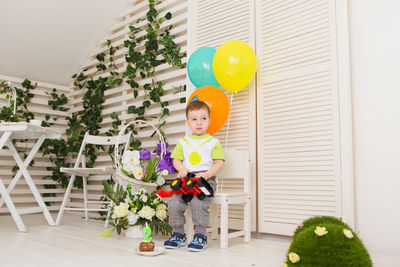 Cute girl holding balloons at home