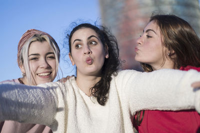 Portrait of smiling young woman with friends against building