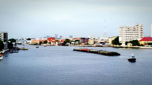 Boats in sea with buildings in background