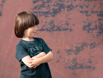Side view of boy standing against wall