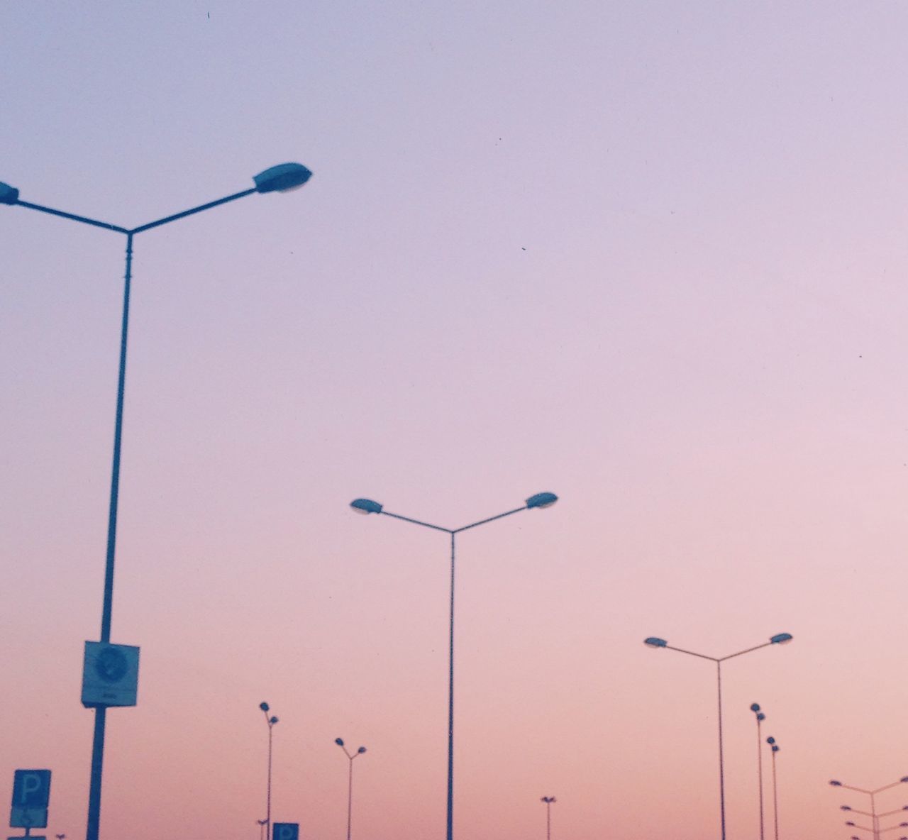 low angle view, street light, lighting equipment, clear sky, pole, copy space, built structure, architecture, electricity, building exterior, no people, sky, outdoors, electric light, high section, in a row, technology, lamp post, communication, day