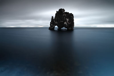 Rock formation in sea against sky