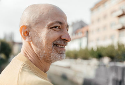 Close-up of a senior man smiling gently, wearing a yellow sweater