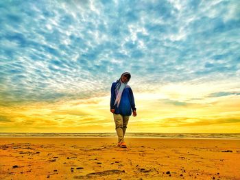 Full length of woman standing at the beach against sky