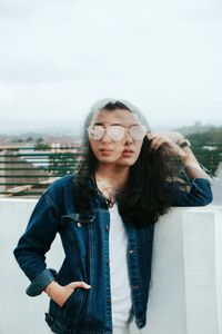 Portrait of beautiful young woman standing against sky