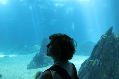 Rear view of girl swimming in aquarium