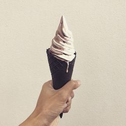 Midsection of person holding ice cream against wall