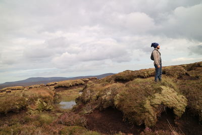Rear view of man walking on mountain against sky