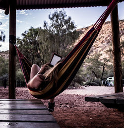 Woman using digital tablet while relaxing in hammock