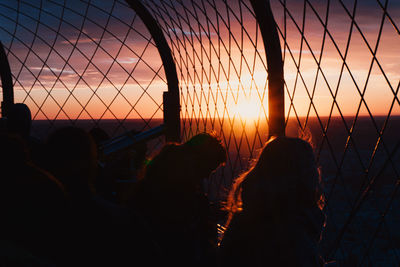 Silhouette people at observation point against orange sky during sunset