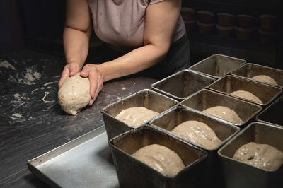 Women's hands carry out actions with raw bread. dough before dipping into a bakery oven