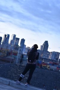 Man and buildings in city against sky