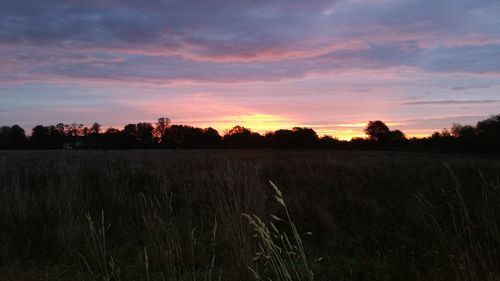 Scenic view of dramatic sky over field during sunset