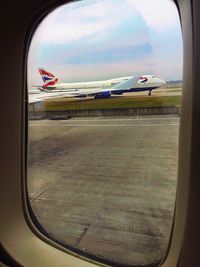 Airplane flying over airport runway against sky