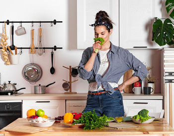 Young and beautiful housewife woman cooking in a white kitchen