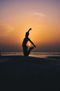 Silhouette man on beach against sky during sunset