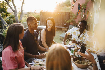 Happy friends talking while enjoying food in dinner party