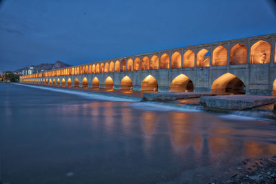 Arch bridge over river against blue sky