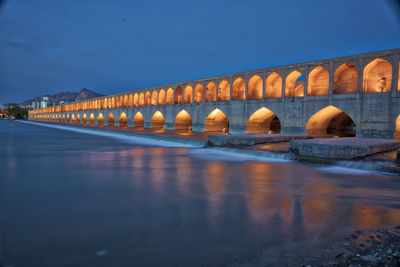 Arch bridge over river against blue sky