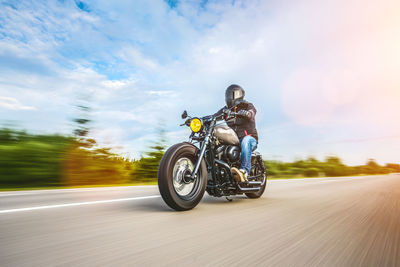 Man riding motorcycle on road against sky