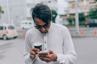 Young man using mobile phone while standing on street